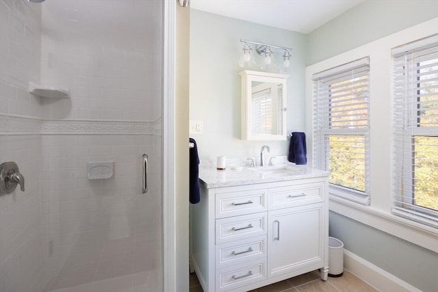 full bath featuring a stall shower, tile patterned flooring, baseboards, and vanity