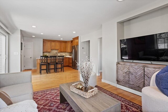 living room with recessed lighting, baseboards, and light wood-type flooring