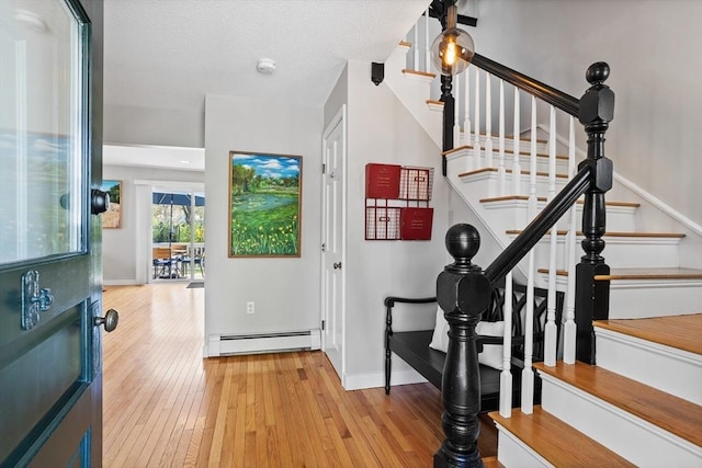 foyer with stairway, baseboards, a baseboard heating unit, and hardwood / wood-style flooring