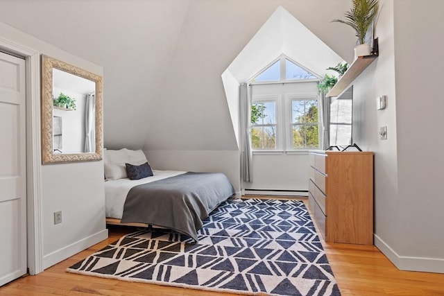 bedroom featuring baseboards, vaulted ceiling, light wood finished floors, and a baseboard radiator