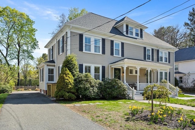 american foursquare style home featuring a porch and roof with shingles