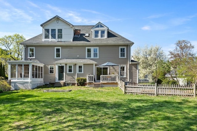 rear view of house with a sunroom, a lawn, fence, and a wooden deck