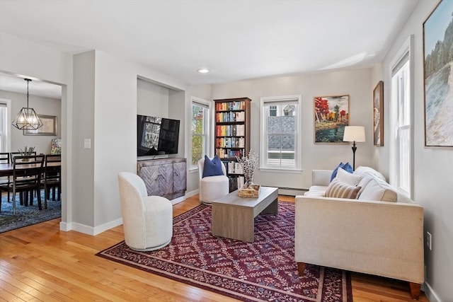 living room featuring baseboards, light wood finished floors, and a healthy amount of sunlight