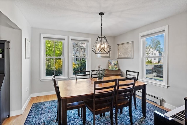 dining area with an inviting chandelier, baseboards, light wood-style flooring, and a wealth of natural light