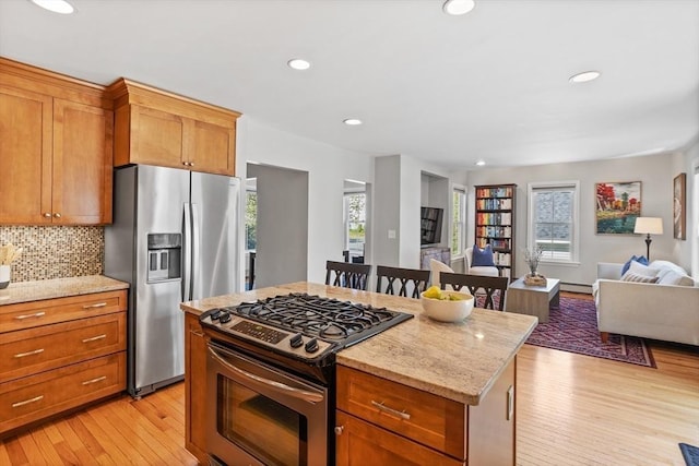 kitchen with tasteful backsplash, open floor plan, light wood-style floors, stainless steel appliances, and recessed lighting