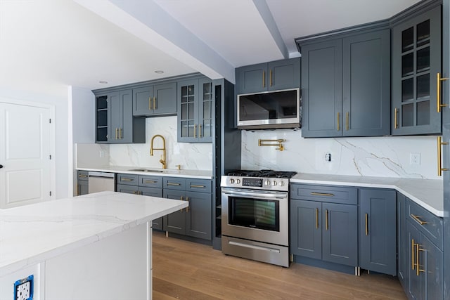 kitchen with decorative backsplash, appliances with stainless steel finishes, wood-type flooring, sink, and beamed ceiling