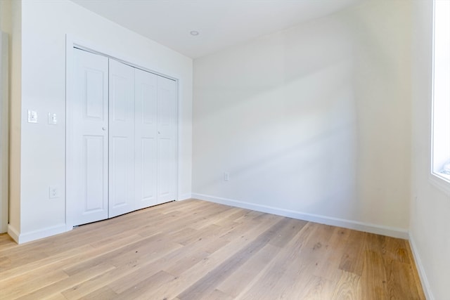 unfurnished bedroom with light wood-type flooring and a closet