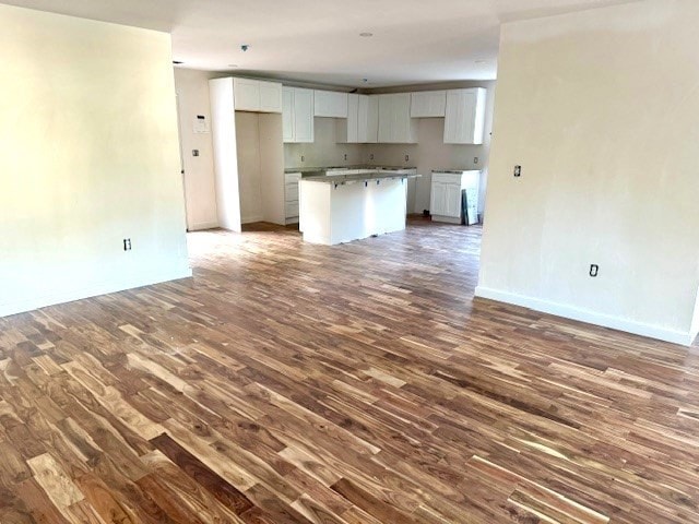 kitchen featuring white cabinets, a center island, and dark wood-type flooring