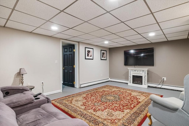 living area with a glass covered fireplace, baseboard heating, recessed lighting, and a paneled ceiling