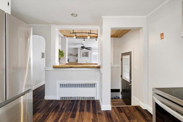 kitchen with stainless steel appliances, rail lighting, radiator, and dark wood-type flooring