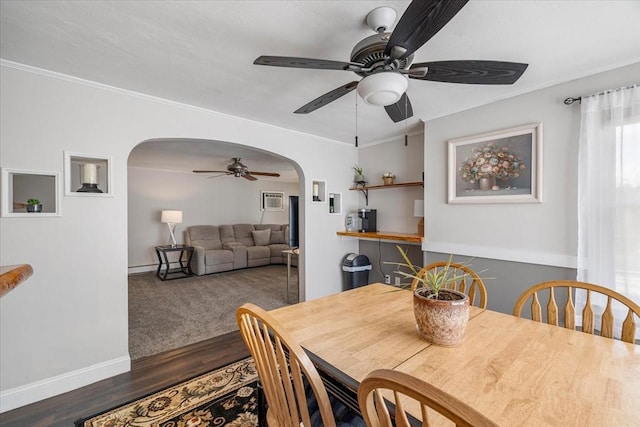 dining area with a ceiling fan, arched walkways, wood finished floors, baseboards, and ornamental molding