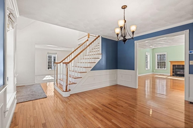 entryway with hardwood / wood-style flooring, a fireplace, stairway, and ornamental molding