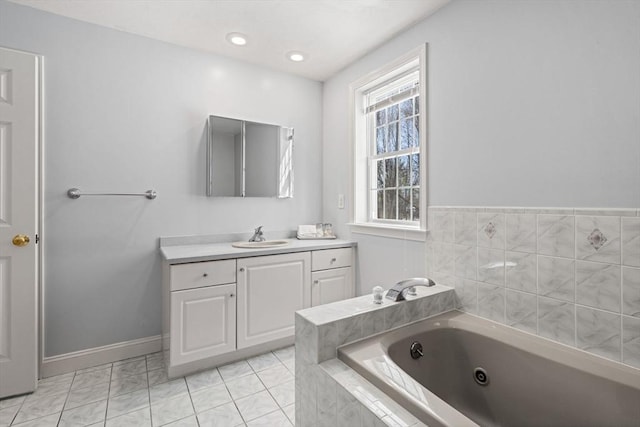 full bath with a jetted tub, recessed lighting, vanity, and baseboards