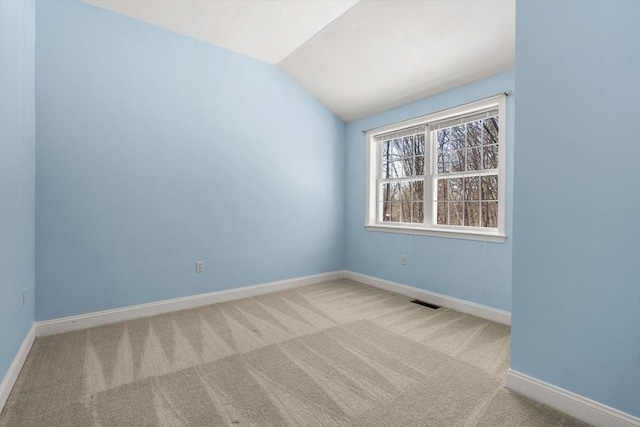 carpeted empty room with lofted ceiling, visible vents, and baseboards