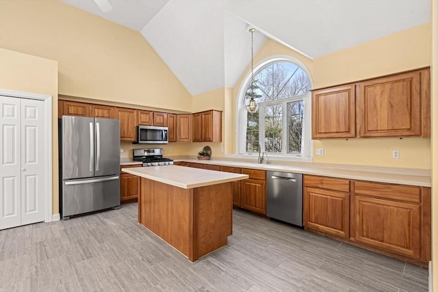 kitchen with a center island, light countertops, appliances with stainless steel finishes, brown cabinetry, and high vaulted ceiling