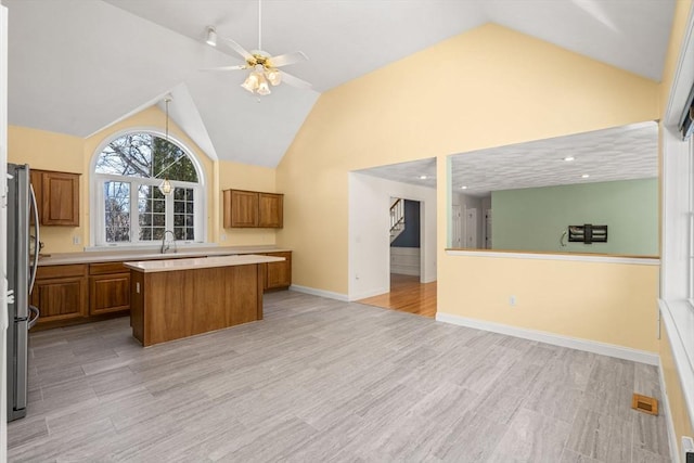 kitchen featuring light countertops, open floor plan, brown cabinets, and a kitchen island