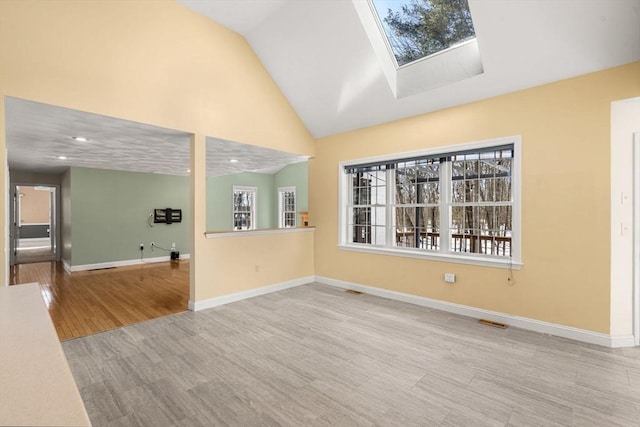 empty room featuring a skylight, baseboards, wood finished floors, and recessed lighting