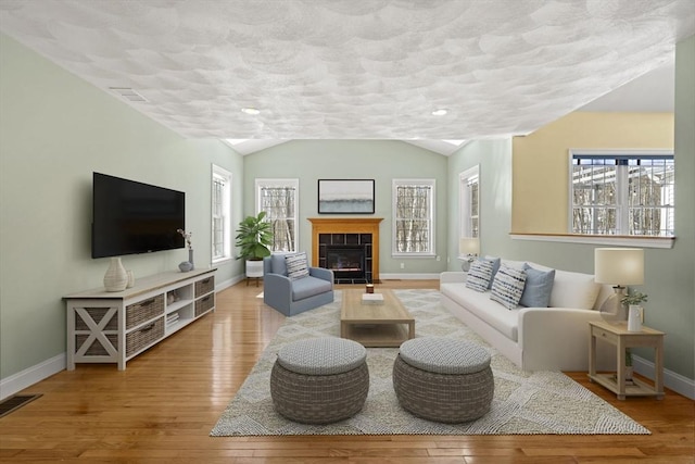 living room featuring lofted ceiling, wood-type flooring, visible vents, and baseboards