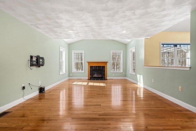 unfurnished living room with baseboards, visible vents, and hardwood / wood-style floors