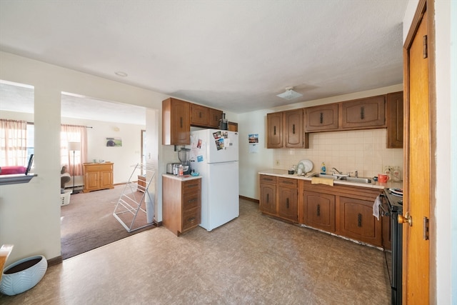 kitchen featuring black electric range, decorative backsplash, white fridge, and sink