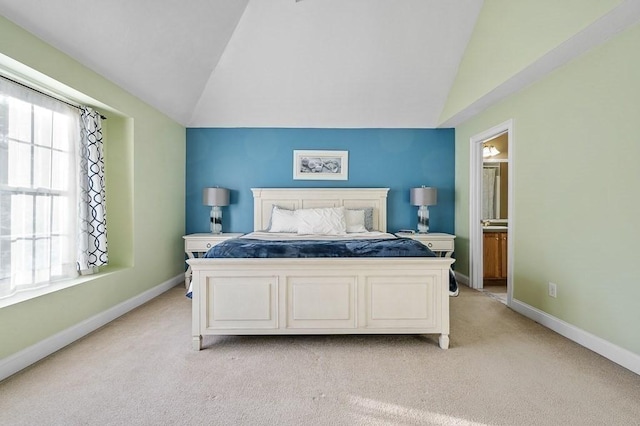 bedroom featuring connected bathroom, light carpet, and lofted ceiling