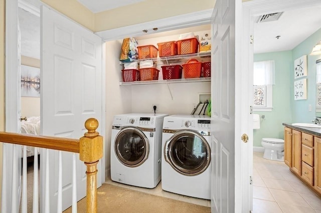 washroom with light tile patterned flooring, washer and dryer, and sink