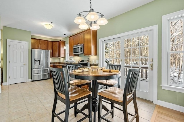 dining space with an inviting chandelier, light tile patterned floors, and a healthy amount of sunlight