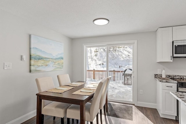 dining room featuring a textured ceiling, dark wood-type flooring, and baseboards