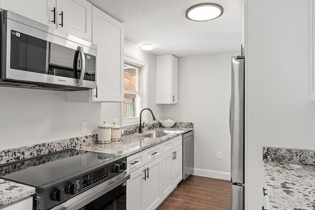 kitchen with stainless steel appliances, light stone counters, and white cabinetry