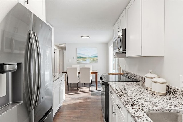 kitchen with stainless steel appliances, white cabinets, and light stone counters