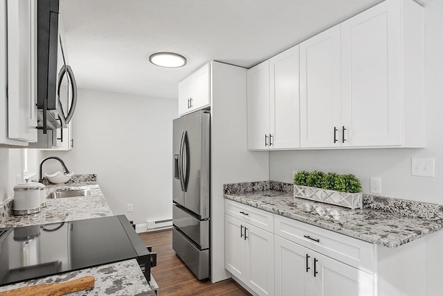 kitchen with stainless steel appliances, baseboard heating, a sink, and white cabinets