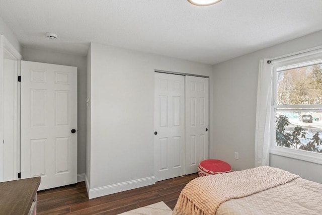 bedroom with dark wood-style floors, baseboards, and a closet