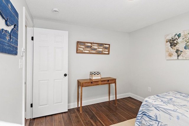 bedroom with dark wood finished floors and baseboards