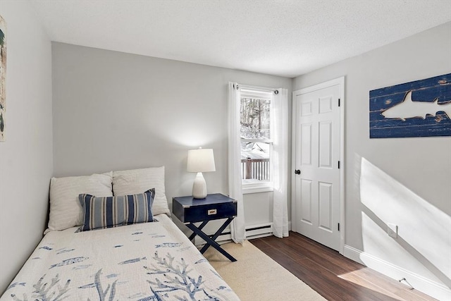 bedroom with dark wood-style floors, a textured ceiling, a baseboard radiator, and baseboards