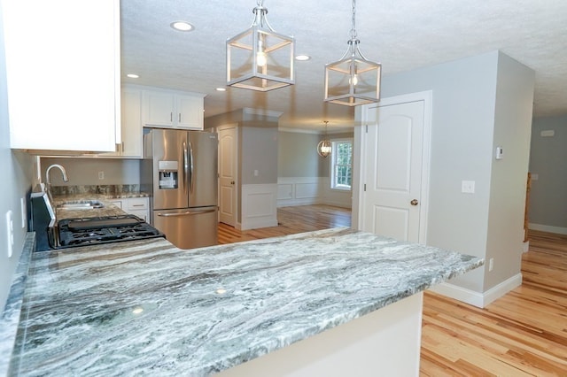 kitchen with stainless steel fridge with ice dispenser, light hardwood / wood-style flooring, sink, and decorative light fixtures