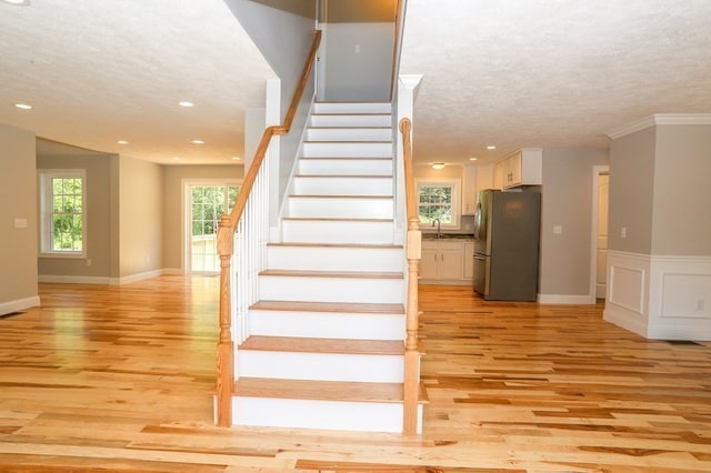 stairs featuring sink, a textured ceiling, and hardwood / wood-style flooring