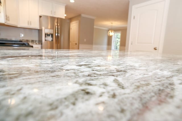 kitchen with pendant lighting, light stone counters, white cabinetry, and stainless steel fridge with ice dispenser