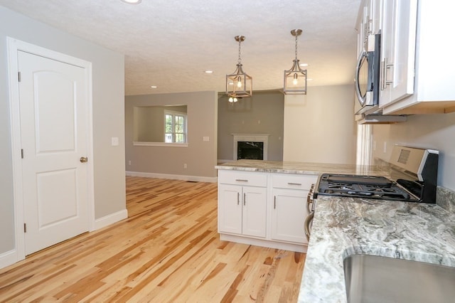 kitchen featuring white cabinets, light stone counters, pendant lighting, and light hardwood / wood-style floors