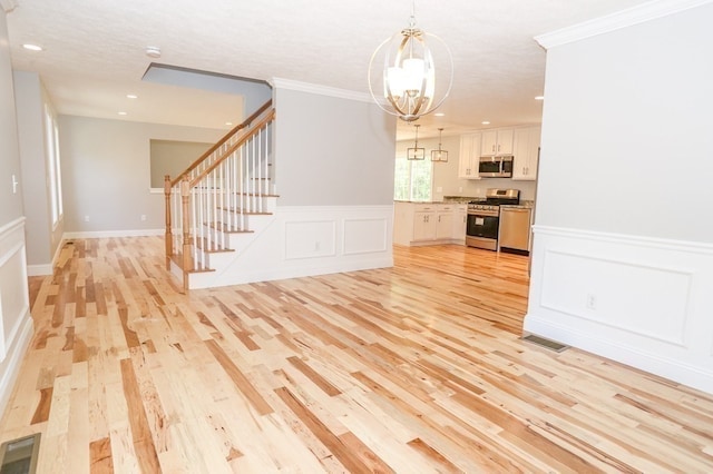 unfurnished living room featuring a chandelier, ornamental molding, and light hardwood / wood-style floors