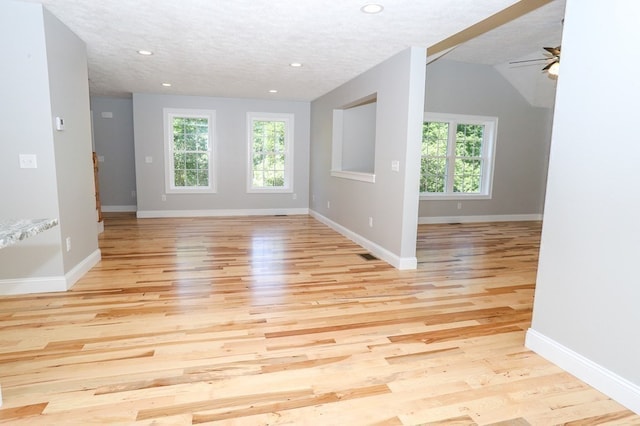 unfurnished room with ceiling fan, light wood-type flooring, lofted ceiling, and plenty of natural light