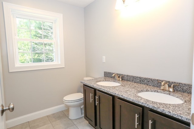 bathroom with tile patterned floors, dual bowl vanity, a healthy amount of sunlight, and toilet