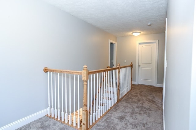 hallway with a textured ceiling and carpet floors