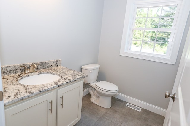 bathroom featuring tile patterned flooring, toilet, vanity, and a healthy amount of sunlight