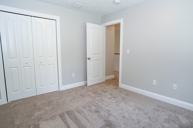 unfurnished bedroom with a textured ceiling, light carpet, and a closet