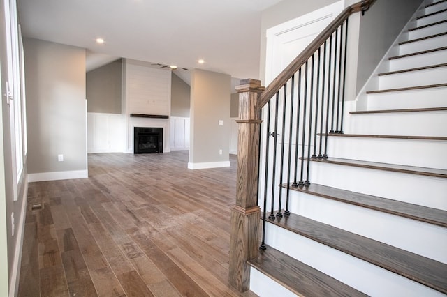 staircase with a fireplace and wood-type flooring