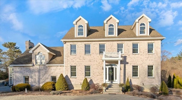 colonial-style house with brick siding and roof with shingles