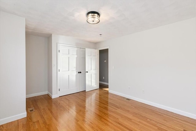 unfurnished bedroom featuring visible vents, baseboards, light wood-style floors, and a closet