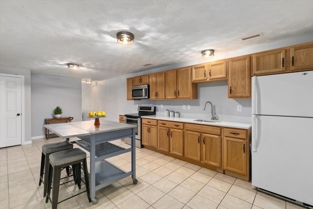 kitchen with visible vents, light countertops, brown cabinets, appliances with stainless steel finishes, and a sink