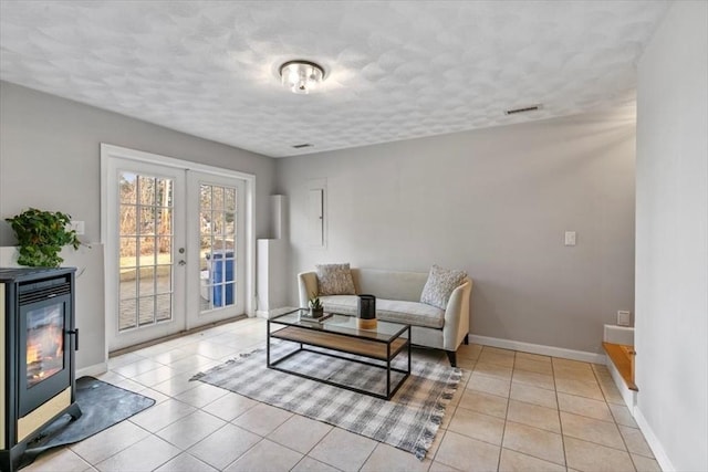 living area with visible vents, baseboards, light tile patterned floors, french doors, and a textured ceiling