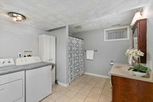 washroom featuring visible vents, a sink, washing machine and dryer, light tile patterned floors, and laundry area